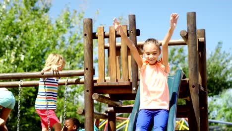 Glücklich-Schulmädchen-spielen-auf-Folie-auf-Spielplatz