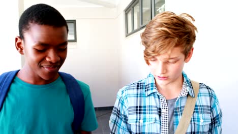 Schoolboys-reading-book-while-walking-in-corridor