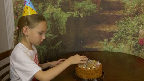 The-girl-removes-the-candles-from-the-cake.-The-girl-pulls-out-candles-from-the-cake-standing-on-the-table.