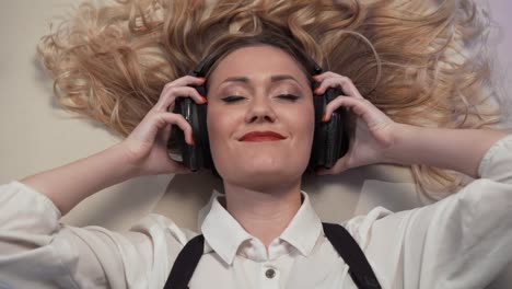 Close-up-Frau-auf-dem-Bett-liegend-langsam-setzt-Kopfhörer-über-den-Ohren,-reagiert-auf-die-Musik,-etwas-schwingt-zusammen-mit-der-Musik