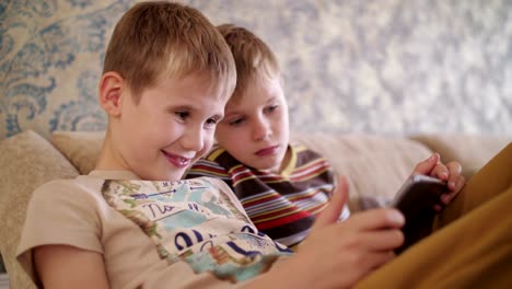 Niños-jugando-en-la-tableta,-en-casa-sentado-en-el-sofá