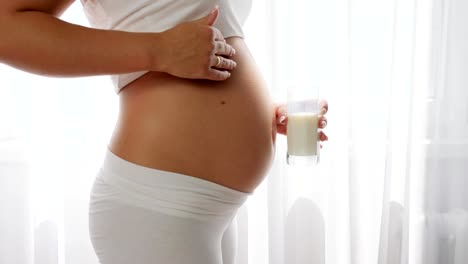 hermosa-mujer-embarazada-frota-su-vientre-y-bebe-un-producto-de-leche