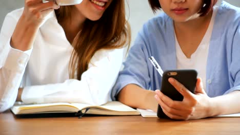 Business-Women-use-mobile-phone-and-writing-report-on-wooden-table.-Asian-women-using-phone-and-cup-of-coffee.-Freelancer-working-in-coffee-shop.-Working-outside-office-lifestyle.