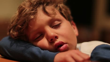 Closeup-of-drooling-sleepy-child-slouched-on-desk-exhausted.-Young-boy-sleeping-profoundly