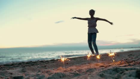 teenager-girl-with-sparklers-dancing-on-the-beach.-shot-in-slow-motion