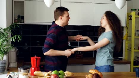 Atractiva-pareja-alegre-joven-divertirse-bailando-durante-la-cocción-en-la-cocina-en-casa