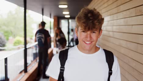 Portrait-Of-Male-Student-Walking-Into-Focus-Outside-Building