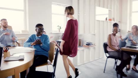 Camera-follows-Caucasian-businesswoman-enter-multi-ethnic-office-doing-funny-dance-walk-of-success-and-celebration-4K