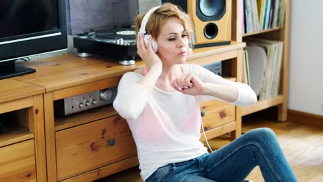 woman-sits-next-to-the-turntable-and-listens-to-music