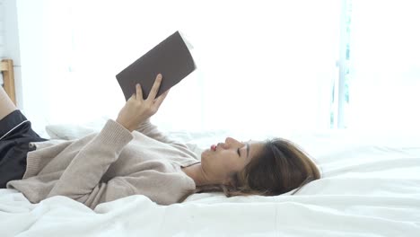 Lifestyle-happy-young-Asian-woman-enjoying-lying-on-the-bed-reading-book-pleasure-in-casual-clothing-at-home.-Relaxing-lifestyle-woman-concept.