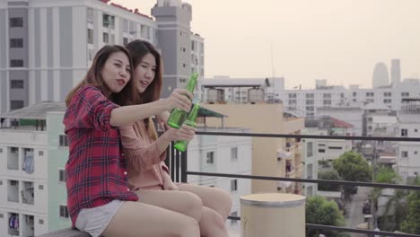 Group-of-young-asian-women-people-dancing-and-raising-their-arms-up-in-air-to-the-music-played-by-dj-at-sunset-urban-party-on-rooftop.-Young-asian-girls-friends-hanging-out-with-drinks.