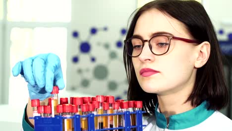 Close-up-of-a-young-female-researcher-examining-test-tubes-with-blood-samples