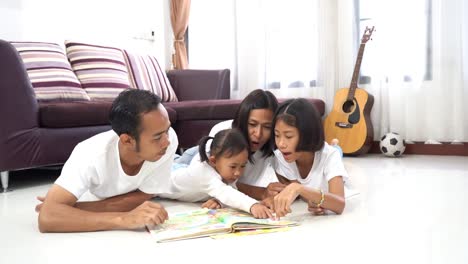 Glückliche-asiatischen-Familie-lesen-ein-Buch-liegen-auf-einer-Etage-zu-Hause