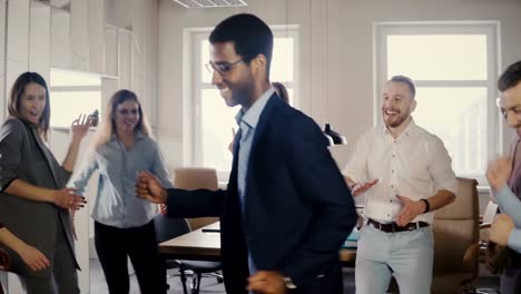 Happy-African-American-executive-dancing-with-colleagues-at-casual-office-party,-celebrating-business-achievement-4K