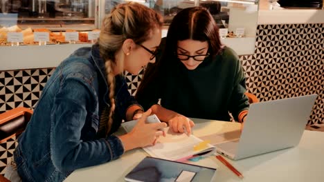 Young-university-students-doing-research-using-laptop-at-urban-café