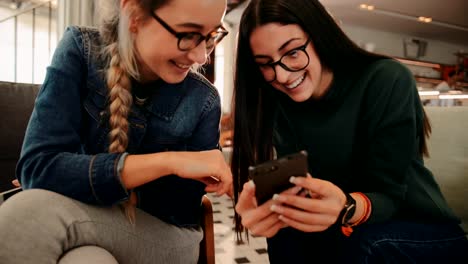 Young-women-with-mobile-phone-having-fun-at-coffee-shop