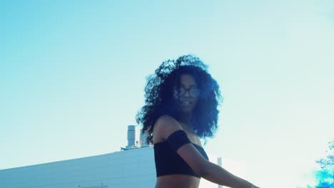 Young-woman-dancing-outside-with-smoke-grenade-at-sunset-on-rooftop-parking-garage