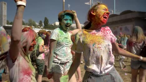 Tres-jóvenes-amigas-multiétnicas-están-saltando-y-bailando-con-polvo-colorido-en-el-festival-de-holi-en-horario-diurno-en-verano,-el-concepto-de-la-amistad,-el-concepto-del-color