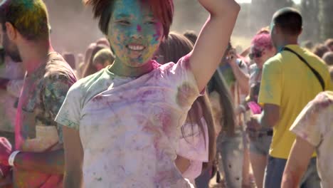 Two-young-multi-ethnic-girlfriends-are-jumping-and-dancing-in-crowd-on-holi-festival-in-daytime-in-summer,-friendship-concept,-holiday-concept