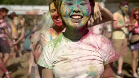 Three-young-happy-multi-ethnic-girlfriends-are-jumping-in-conga-line-on-holi-festival-in-daytime-in-summer,-friendship-concept,-holiday-concept