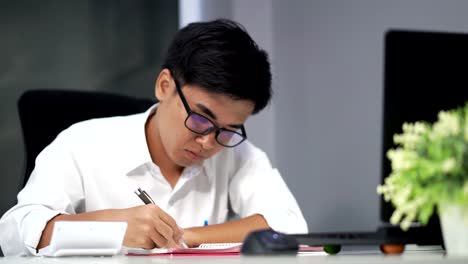 young-man-studying-and-writing-on-notebook-with-laptop-computer