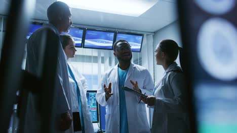 Low-Angle-Shot-of-the-Meeting-of-the-Team-of-Medical-Scientists-in-the-Brain-Research-Laboratory.-Neurologists-/-Neuroscientists-Having-Analytical-Discussion-Surrounded-by-Monitors-Showing-CT,-MRI-Scans.