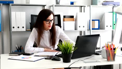 geschäftsfrau-füllen-Dokumente-und-arbeiten-am-Laptop-im-modernen-Büro