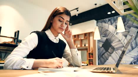 La-atractiva-mujer-que-trabaja-en-el-escritorio-con-un-moderno-ordenador-portátil