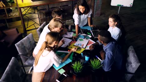 Multiracial-team-is-analyzing-charts-and-graphs-during-business-meeting-then-clapping-hands-and-doing-high-five-expressing-support,-unity-and-successful-work.