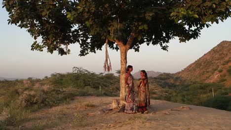 Two-girlfriends-talk-on-the-mobile-phone-happy-sad-waiting-call-exchange-phone-jungle-park-on-a-deserted-hill-top-for-lover-on-a-summer-hot-day-teamwork-handheld-stabilized-two-shot-wide