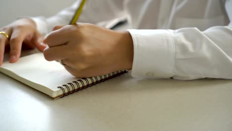 Businessman-hand-writing-to-do-list-notes-in-notebook-with-pencil.