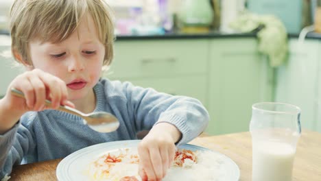 Niedlichen-kleinen-Jungen-essen-am-Tisch-im-Haus