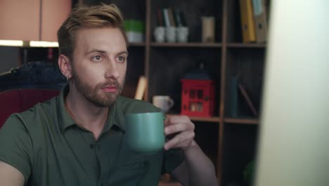 Creative-designer-drinking-tea-in-startup-office.-Man-looking-on-computer-screen