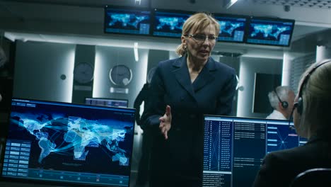 Female-Chief-Operative-Officer-talks-to-Cyber-Security-Dispatchers-Working-on-Personal-Computer-Showing-Traffic-Data-Flow-in-the-System-Control-Room.