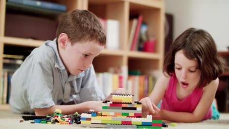 Two-kids-playing-with-plastic-block-bricks-at-home