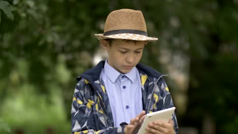 farmer-boy-in-a-hat-uses-a-tablet-in-the-garden,-checks-the-crop