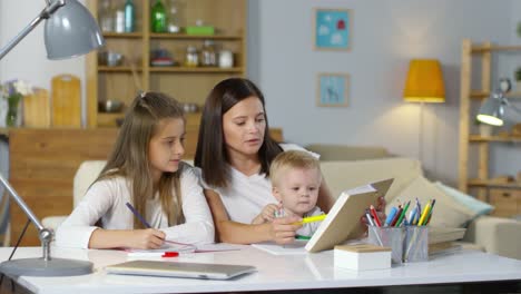 Beautiful-Mom-Helping-Daughter-with-Homework-and-Taking-Care-on-Baby-Son