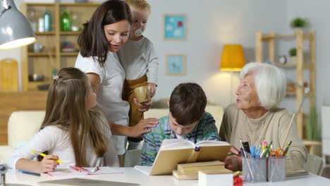 Niños-estudiando-en-casa-con-la-abuela-mientras-la-madre-Coddling-un-bebé