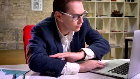 Calm-caucasian-businessman-is-sleeping-at-the-workplace-alone-and-continue-working-with-computer-after-a-while