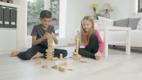 zwei-junge-glückliche-Kinder-Bruder-und-Schwester-zusammen-Spaß-zu-Hause-mit-einem-hölzernen-Backstein-Spielzeug-Spiel