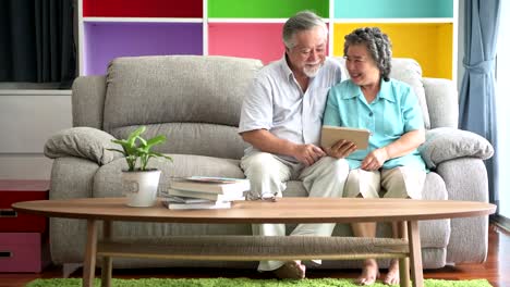 Senior-couple-sitting-and-watching-tablet-in-living-room.