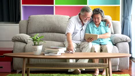 Senior-couple-sitting-and-watching-tablet-in-living-room.