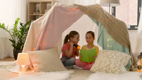 happy-girls-reading-book-in-kids-tent-at-home