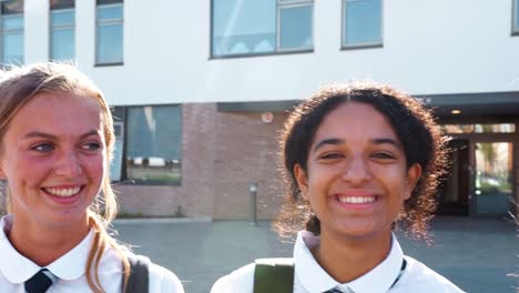 Retrato-de-sonriente-mujer-estudiantes-con-uniforme-exterior-Colegio-edificio