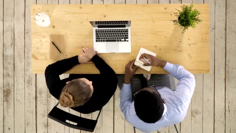 Two-entrepreneurs-sitting-together-working-in-an-office-desk-putting-notes-to-notebook