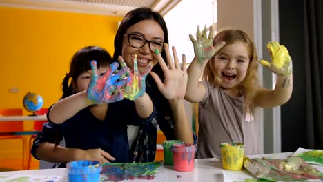 Kids-and-teacher-with-hands-in-paint-at-art-lesson