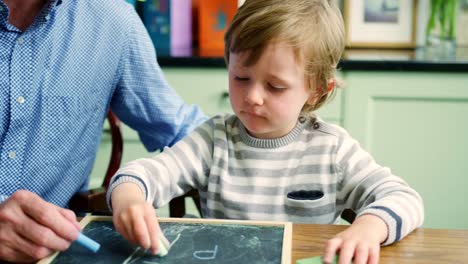 Padre-hijo-de-enseñar-a-escribir-en-la-pizarra-y-la-tiza-usando