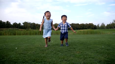 Freudige-asiatische-Kinder-laufen-zusammen-im-park