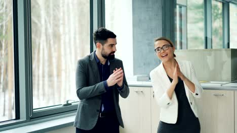 Linda-pareja-de-colegas-hombre-y-mujer-con-trajes-está-bailando-en-la-oficina-de-divertirse-juntos-disfrutando-de-jornada-de-trabajo.-Personas,-trabajo-y-fiesta-concepto.