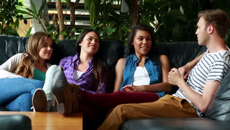 Happy-friends-sitting-on-the-couch-speaking